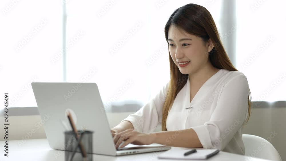 Young asian beautiful business woman working with laptop sitting at home and note on book. Smiling charming happy young female doing homework meeting conference with team at home. Young asian beautiful business woman working with laptop sitting at home and note on book. Smiling charming happy young female doing homework meeting conference with team at home.