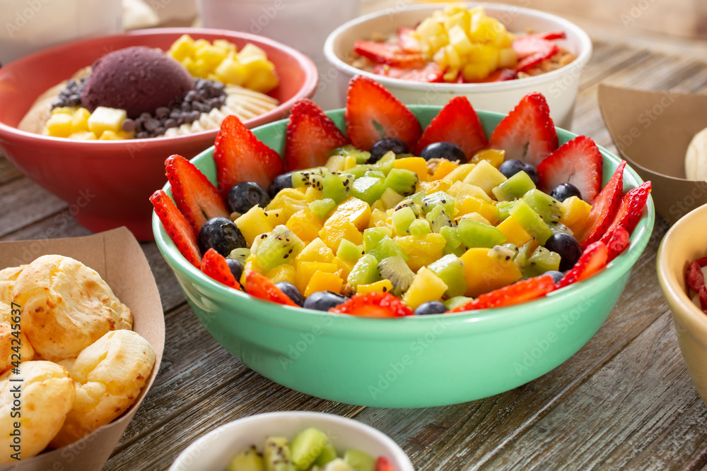 A view of a large fruit bowl, among other delicious sweet and savory sides found in a Brazilian cafe. A view of a large fruit bowl, among other delicious sweet and savory sides found in a Brazilian cafe.