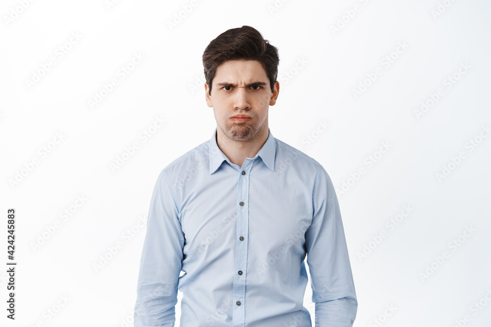 Angry and displeased office worker, frowning and looking mad, standing bothered or insulted, losing temper, boiling from anger, standing over white background Angry and displeased office worker, frowning and looking mad, standing bothered or insulted, losing temper, boiling from anger, standing over white background