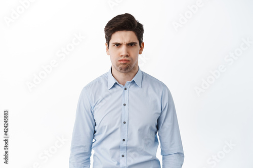 Angry and displeased office worker, frowning and looking mad, standing bothered or insulted, losing temper, boiling from anger, standing over white background