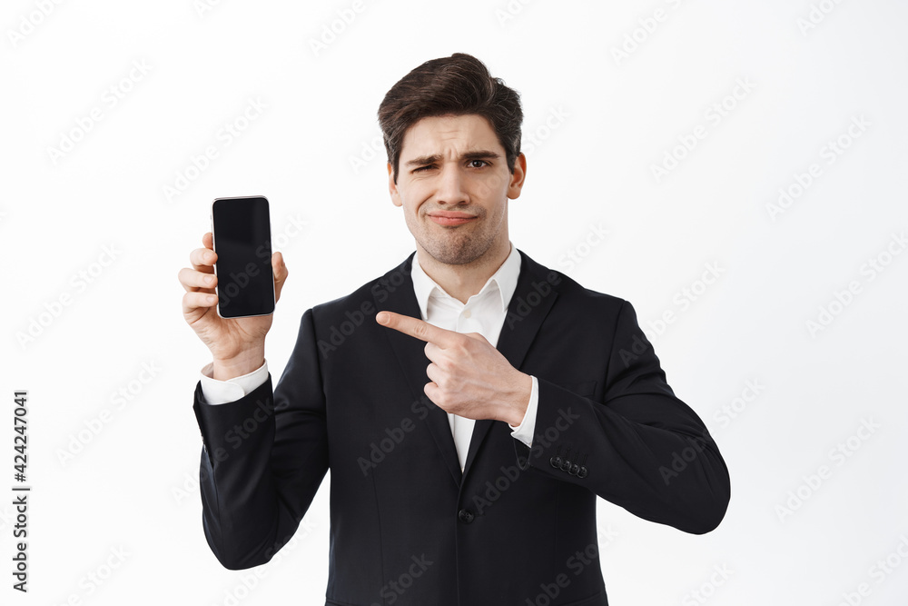Disappointed frowning business man pointing at empty phone screen, judging bad promo, dislike website, lame promo deal, standing over white background Disappointed frowning business man pointing at empty phone screen, judging bad promo, dislike website, lame promo deal, standing over white background