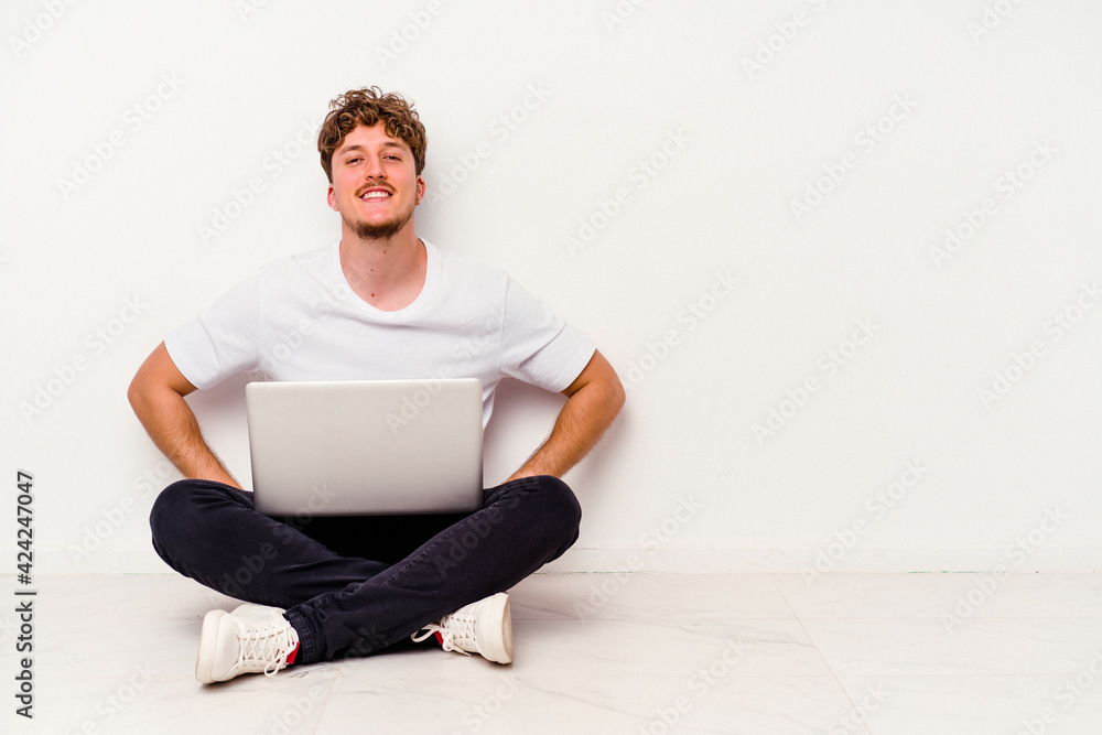 Young caucasian man sitting on the floor holding on laptop isolated on white background confident keeping hands on hips. Young caucasian man sitting on the floor holding on laptop isolated on white background confident keeping hands on hips.
