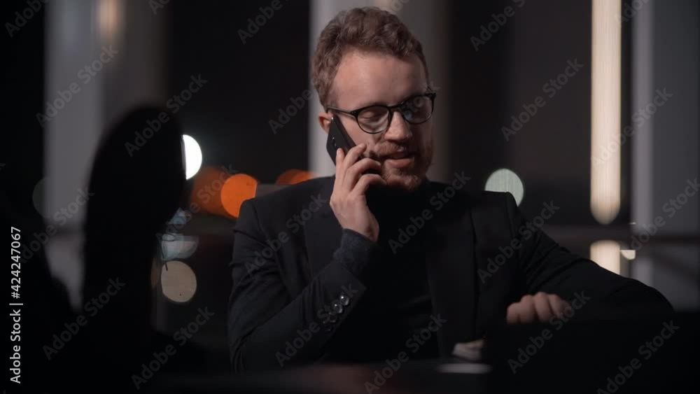 handsome stylishyoung man in a business suit talking on the phone sitting at the table handsome stylishyoung man in a business suit talking on the phone sitting at the table