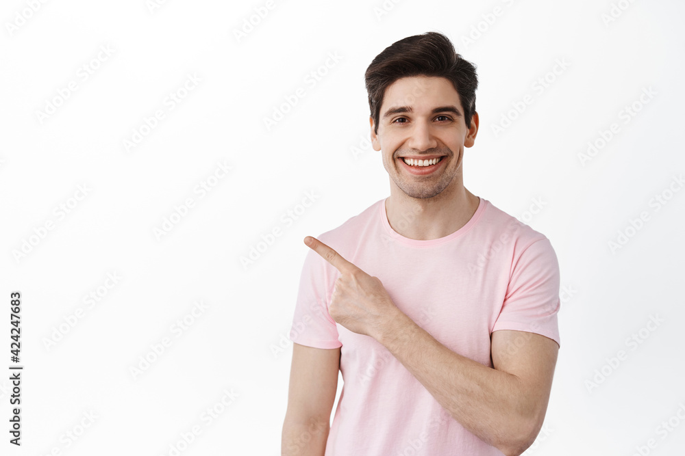 Adult candid caucasian man smiles and points aside, shows copy spaces, way to your logo, standing over white background Adult candid caucasian man smiles and points aside, shows copy spaces, way to your logo, standing over white background