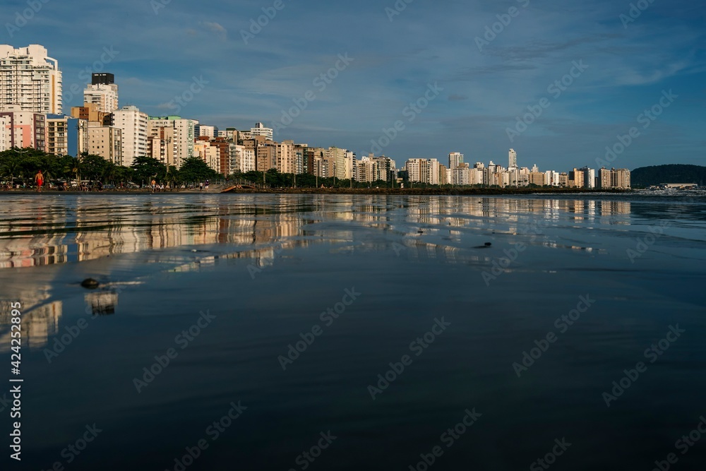 Late afternoon at Santos beach with waterfront buildings illuminated by sunlight in the blue sky.
