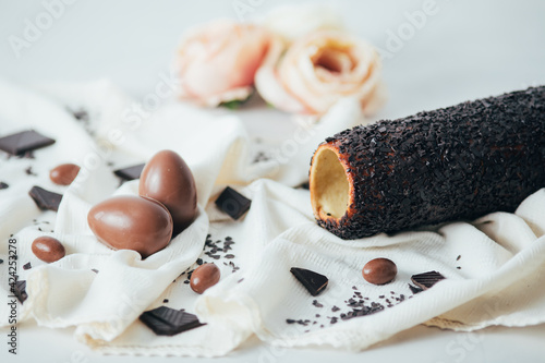 Traditional Hungarian kurtos kalacs known as chimney cake on a rustic tablecloth and chocolate Easter eggs.  photo