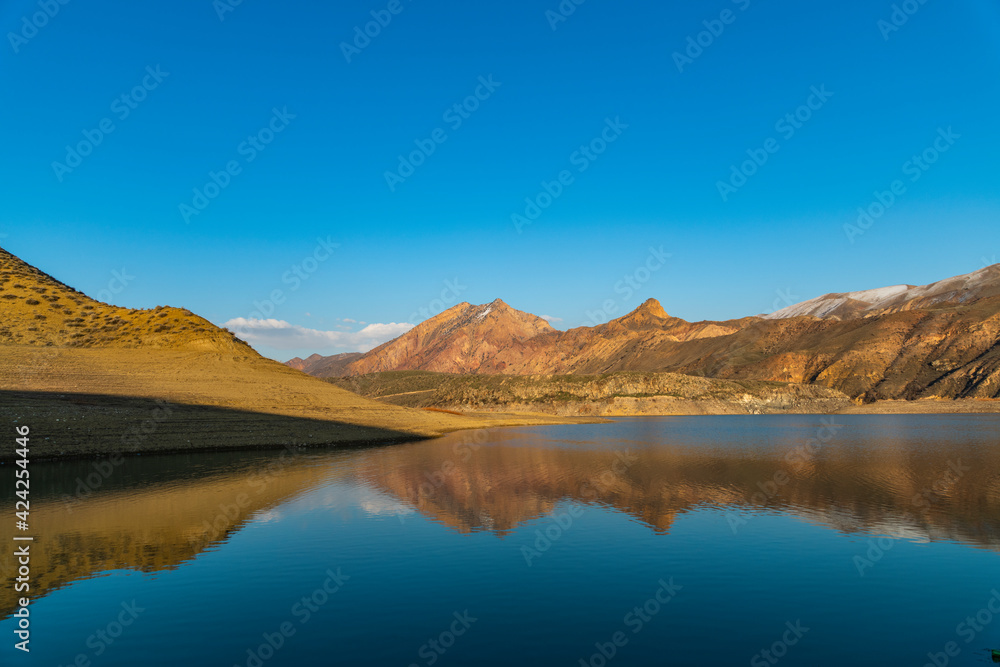 Beautiful panoramic view on the blues clear sky, lake and mountais, reflection in the water.
