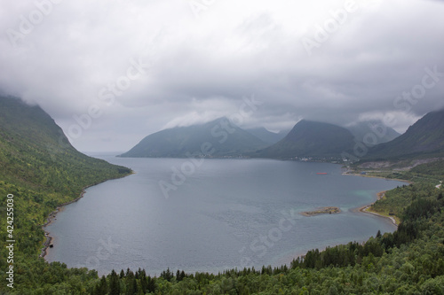 Coast of Norwegian Sea. Magnificent mountain chain at background. Gloomy weather, grey clouds. Island Senja, Troms, northern Norway, Europe. Travel, tourism concept.