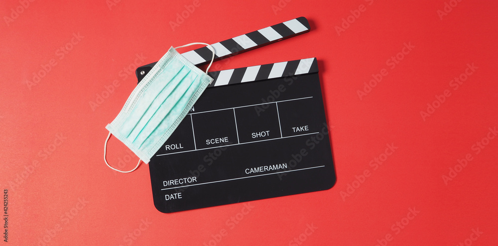 Black clapper board or movie slate and face mask on red background.It is use in video production or movie and cinema industry.