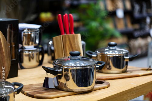 kitchenware, cookware set on wood table. Beautiful modern new pans. Interior and design of modern home kitchen. Blurred background, selective focus