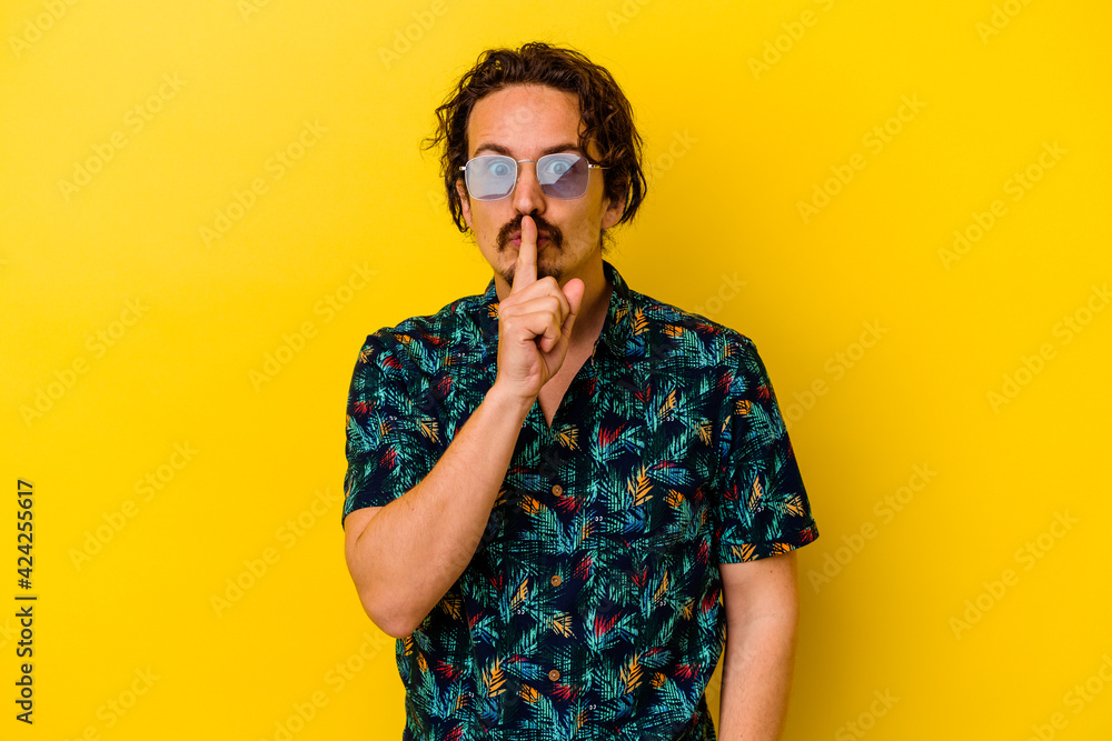 Fototapeta premium Young caucasian man wearing summer clothes isolated on yellow background keeping a secret or asking for silence.