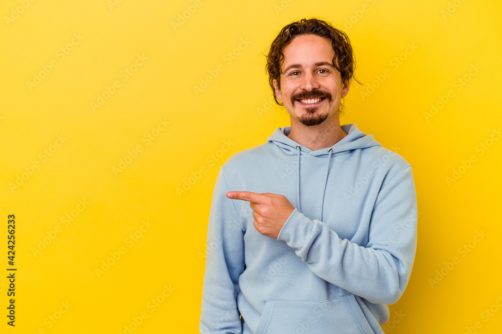 Young caucasian man isolated on yellow background smiling and pointing aside, showing something at blank space. Young caucasian man isolated on yellow background smiling and pointing aside, showing something at blank space.