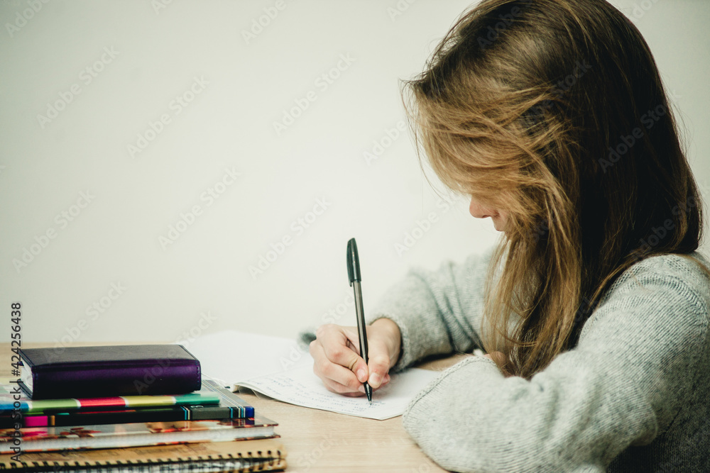 teen girl writing at the table on a white background