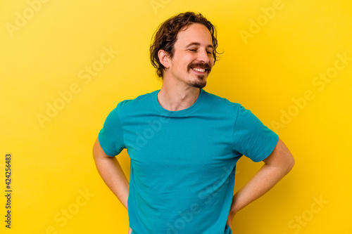 Young caucasian man isolated on yellow background confident keeping hands on hips.