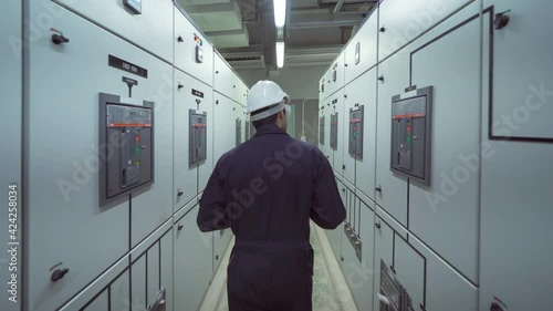 An engineer man or worker, people working in electrical room. Power energy motor machinery cabinets in control or server room, operator station network and circuit center in industry factory system.
