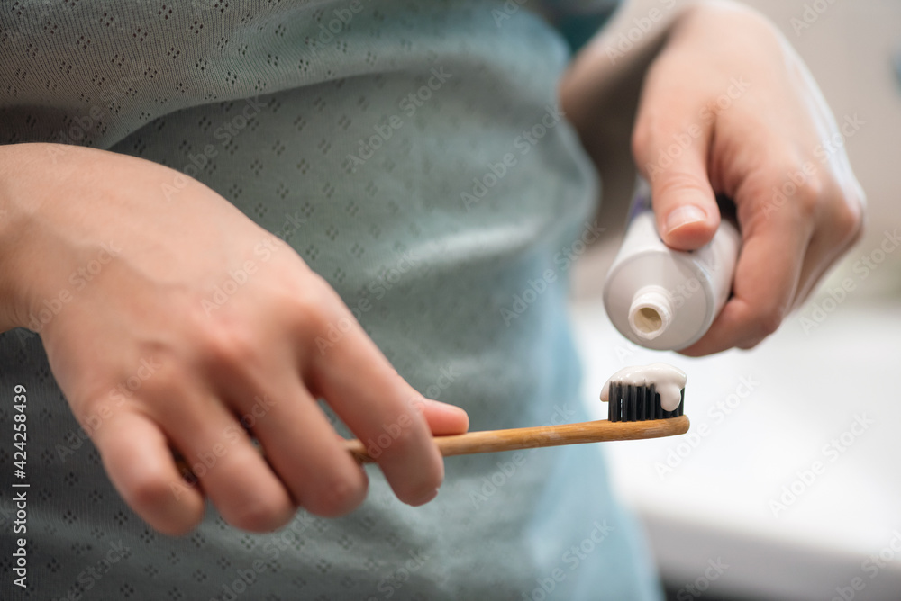 Woman will squeeze the toothpaste from the tube onto the toothbrush close up. Woman will squeeze the toothpaste from the tube onto the toothbrush close up.