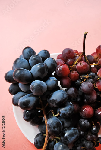 Black and red grapes on a pink background.