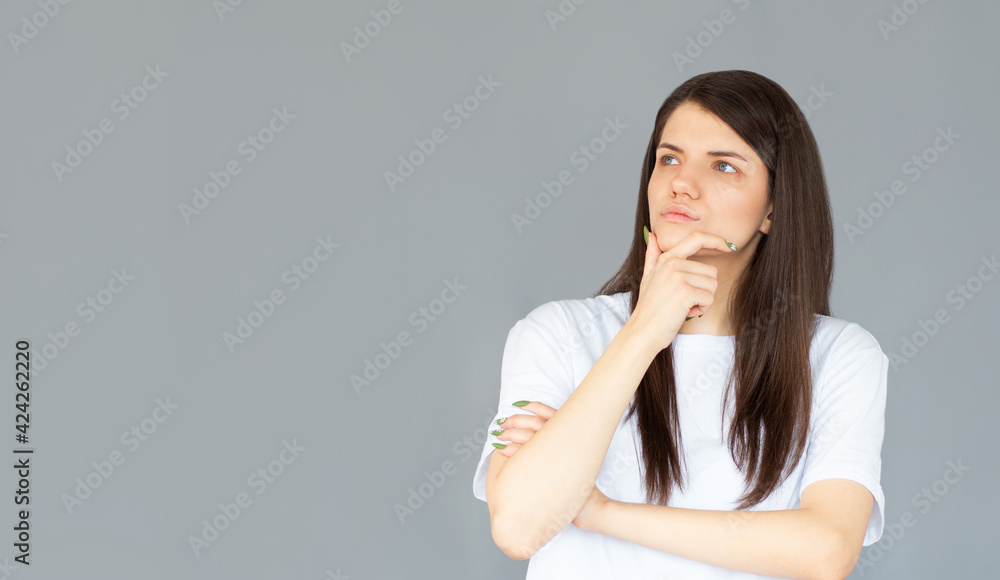 Thoughtful model in studio looking away. hand near the face. isolated gray background Thoughtful model in studio looking away. hand near the face. isolated gray background