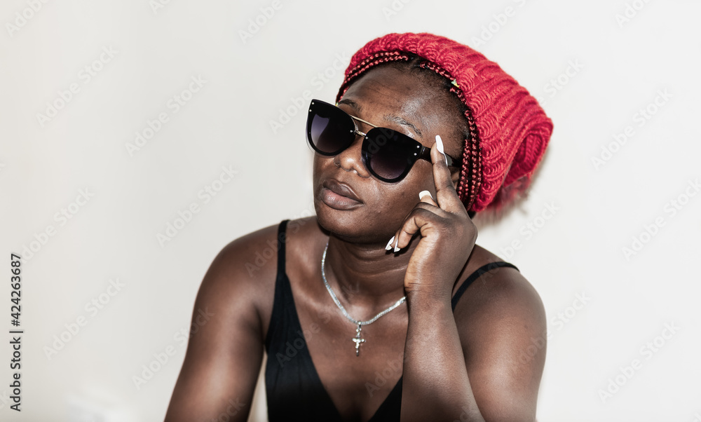 Africa woman with sunglasses sitting and thinking about wearing a winter hat in Accra Ghana West Africa