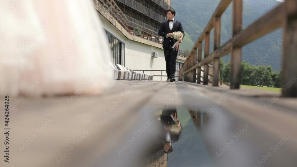 The groom approaches the bride on their wedding day. Reflection in a puddle The groom approaches the bride on their wedding day. Reflection in a puddle
