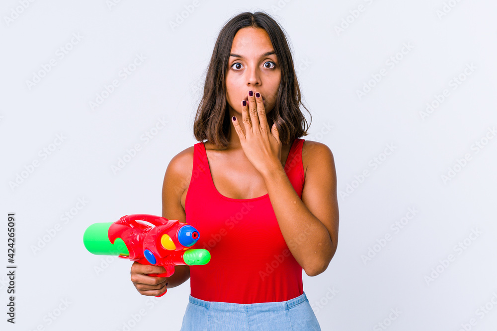 Young mixed race woman holding a water gun isolated shocked, covering mouth with hands, anxious to discover something new. Young mixed race woman holding a water gun isolated shocked, covering mouth with hands, anxious to discover something new.