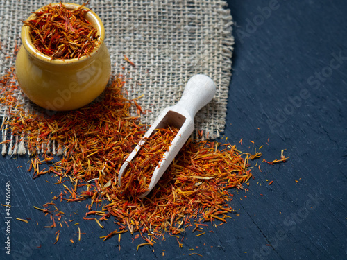 Dried saffron spices in a wooden spoon on a black background photo