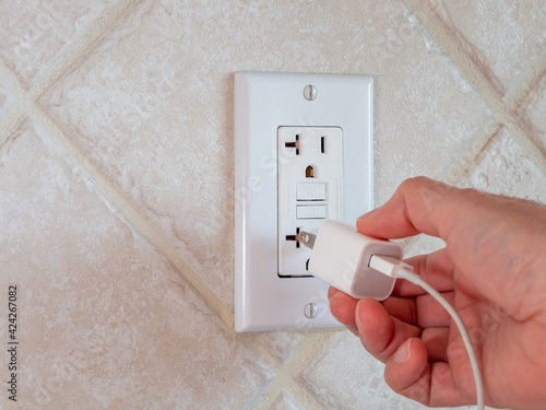 фотографія Plugging in electrical usb cord and charger plug in wall outlet