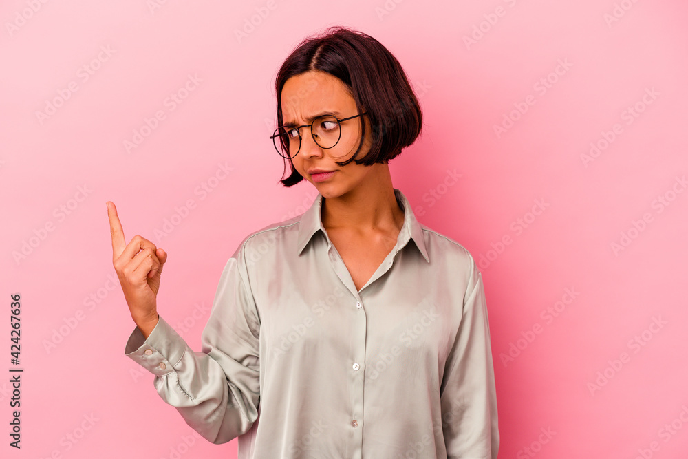 Young mixed race woman isolated on pink background pointing with finger at you as if inviting come closer. Young mixed race woman isolated on pink background pointing with finger at you as if inviting come closer.