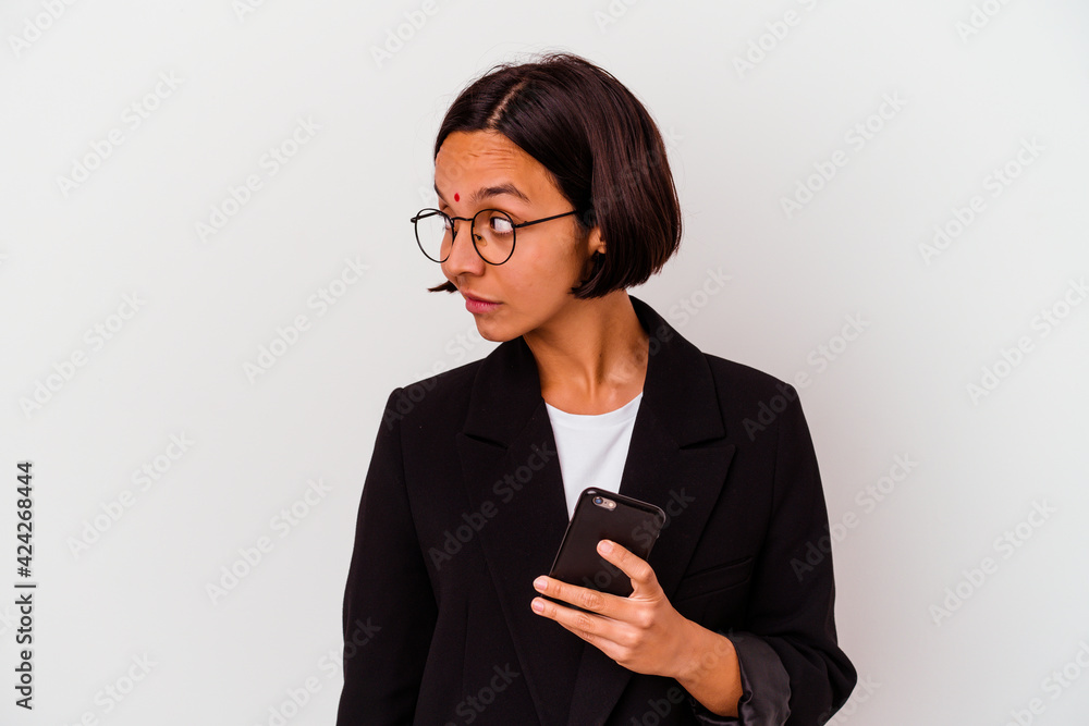 Young indian business woman holding a phone isolated Young business indian woman holding a phone isolated looks aside smiling, cheerful and pleasant. Young indian business woman holding a phone isolated Young business indian woman holding a phone isolated looks aside smiling, cheerful and pleasant.