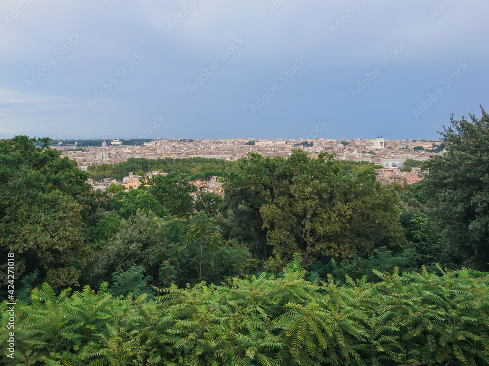 View on Rome from Belvedere del Gianicolo scenic viewing spot. With greenery and dark epic clouds. Travel Italy