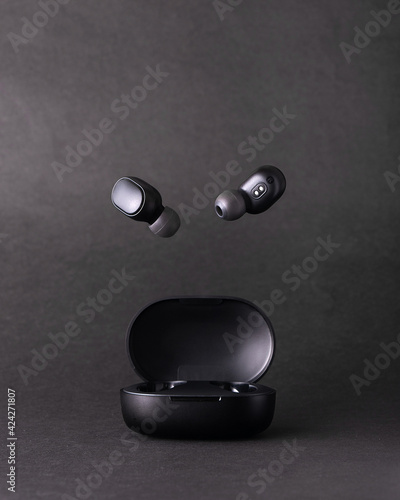 Obraz na plátne Auriculares bluetooth volando en estudio fondo negro