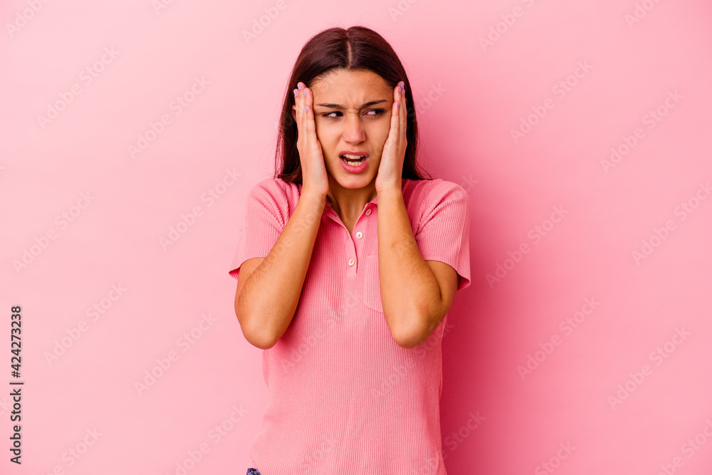 Young Indian woman isolated on pink background covering ears with hands trying not to hear too loud sound. Young Indian woman isolated on pink background covering ears with hands trying not to hear too loud sound.