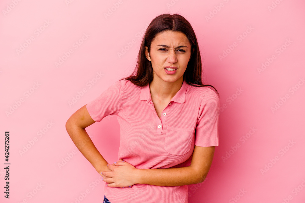 Young Indian woman isolated on pink background having a liver pain, stomach ache. Young Indian woman isolated on pink background having a liver pain, stomach ache.