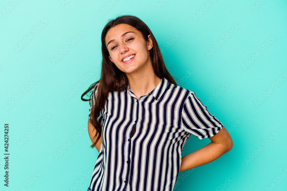 Young Indian woman isolated on blue background confident keeping hands on hips. Young Indian woman isolated on blue background confident keeping hands on hips.