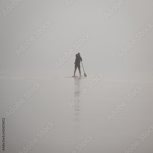 Single person paddle boarding in the fog.