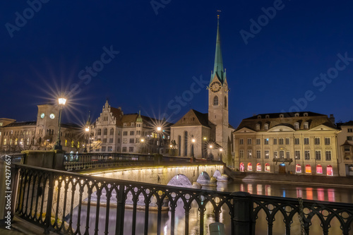 View over bridge and the water of the lake at Fraumunster Church in Zurich, Switzerland in the blue hour night time