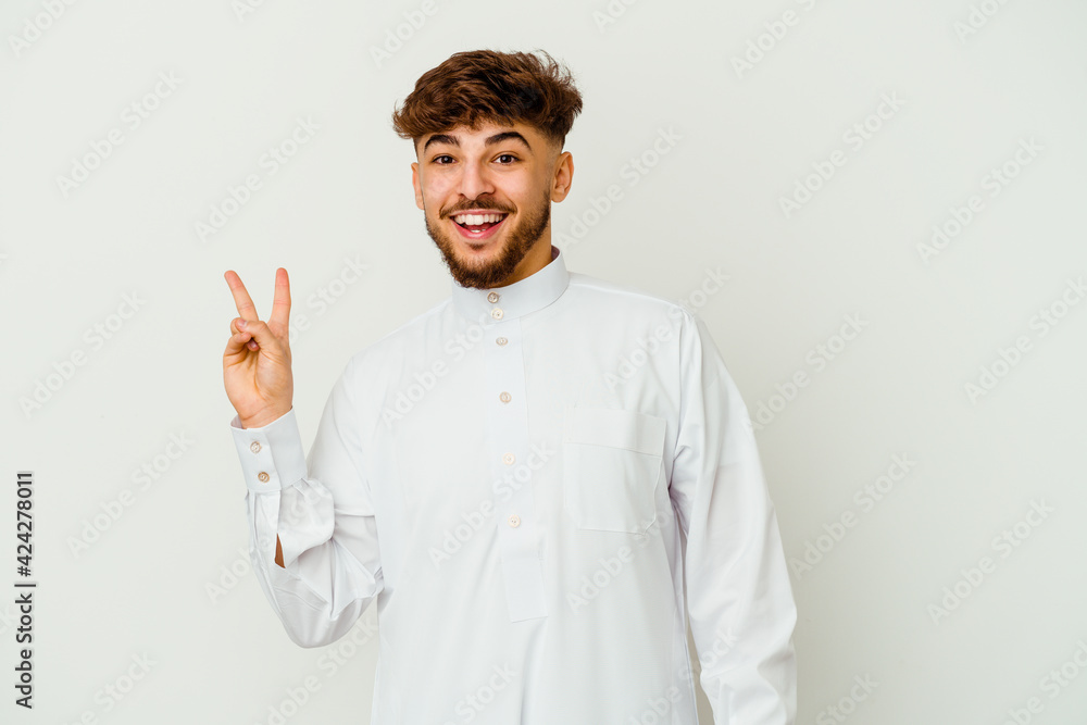 Young Moroccan man wearing a typical arab clothes isolated on white background joyful and carefree showing a peace symbol with fingers. Young Moroccan man wearing a typical arab clothes isolated on white background joyful and carefree showing a peace symbol with fingers.