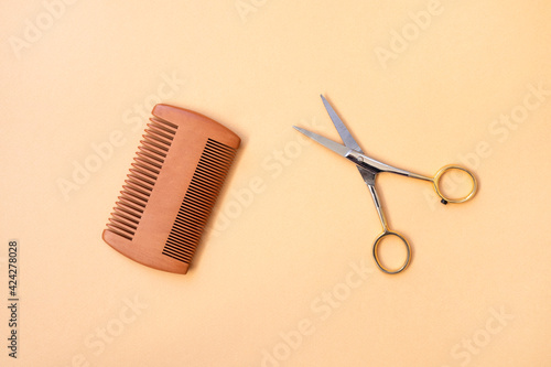Comb and scissors on collor background.