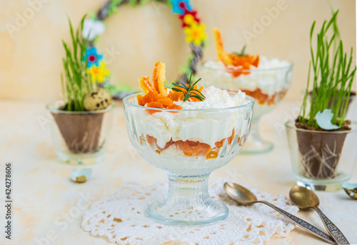 Finnish cottage cheese Easter dessert with whipped cream and dried apricots in glass bowls on a light concrete background. Happy Easter.