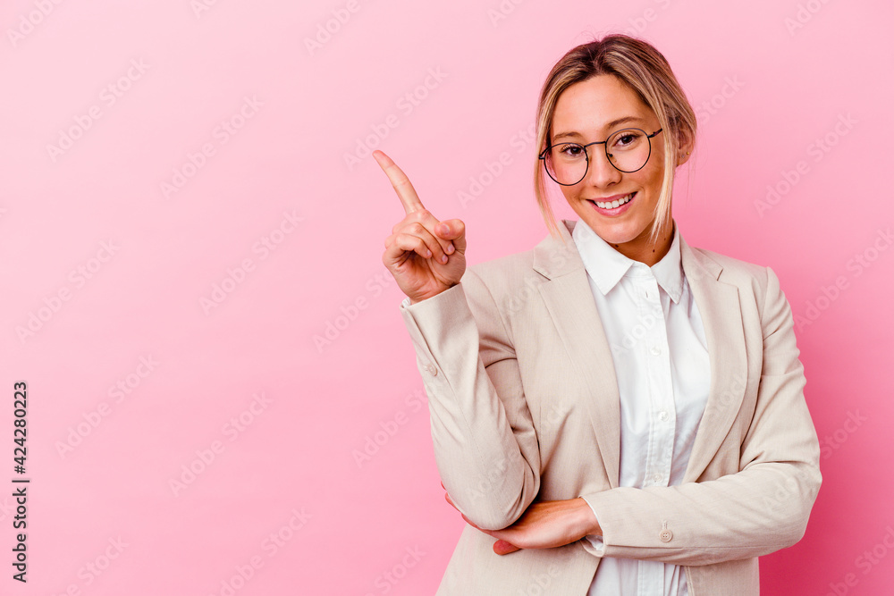 Young caucasian mixed race business woman isolated on pink background smiling cheerfully pointing with forefinger away. Young caucasian mixed race business woman isolated on pink background smiling cheerfully pointing with forefinger away.