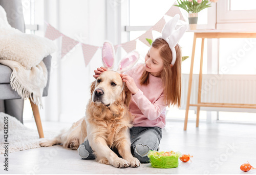 Little girl with golden retriever dog at Easter