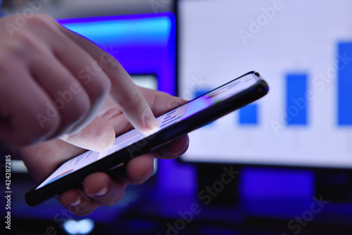 Accountant hand using smartphone and analyzes investment data.
