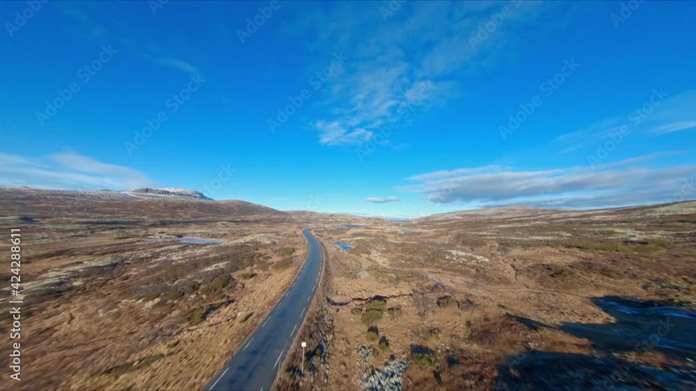 FPV drone following a empty mountain road in rondane national park blue sky sunny FPV drone following a empty mountain road in rondane national park blue sky sunny