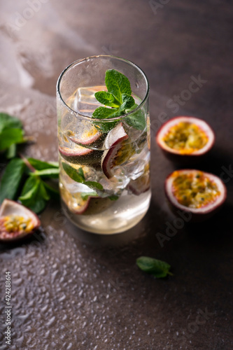 refreshing drink with passion fruit. cocktail with tropical fruit on a dark background. with green mint leaves. vertical position