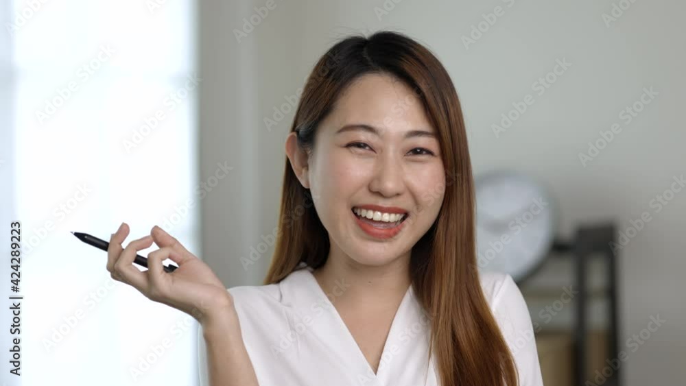 Young asian business woman standing and post front of desk in the office. Smiling charming happy young female working in home office. Young asian business woman standing and post front of desk in the office. Smiling charming happy young female working in home office.