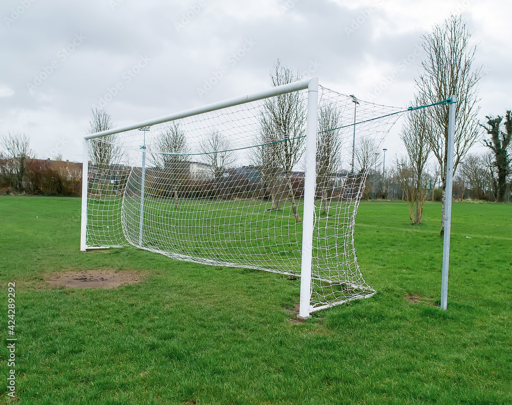 Fototapeta premium Football goal post on a training ground. Worn out grass on a keeper spot. Soccer theme background