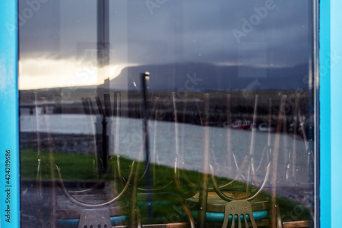 Wooden brown chairs on a table in a closed during covid 19 lock down restaurant. Benbulben reflection on the glass.