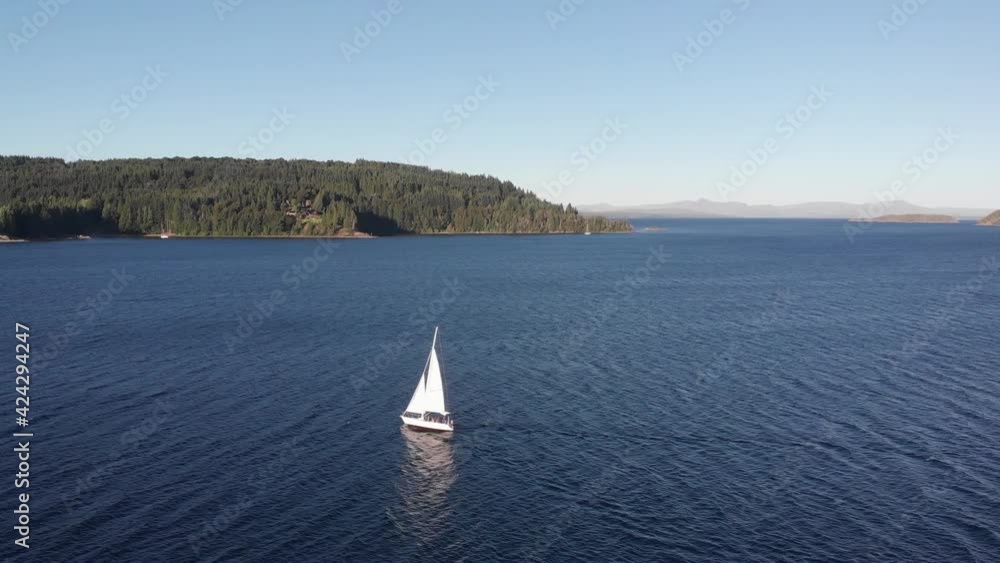 Aerial flight tracks bright white sailboat sailing on deep blue lake Aerial flight tracks bright white sailboat sailing on deep blue lake