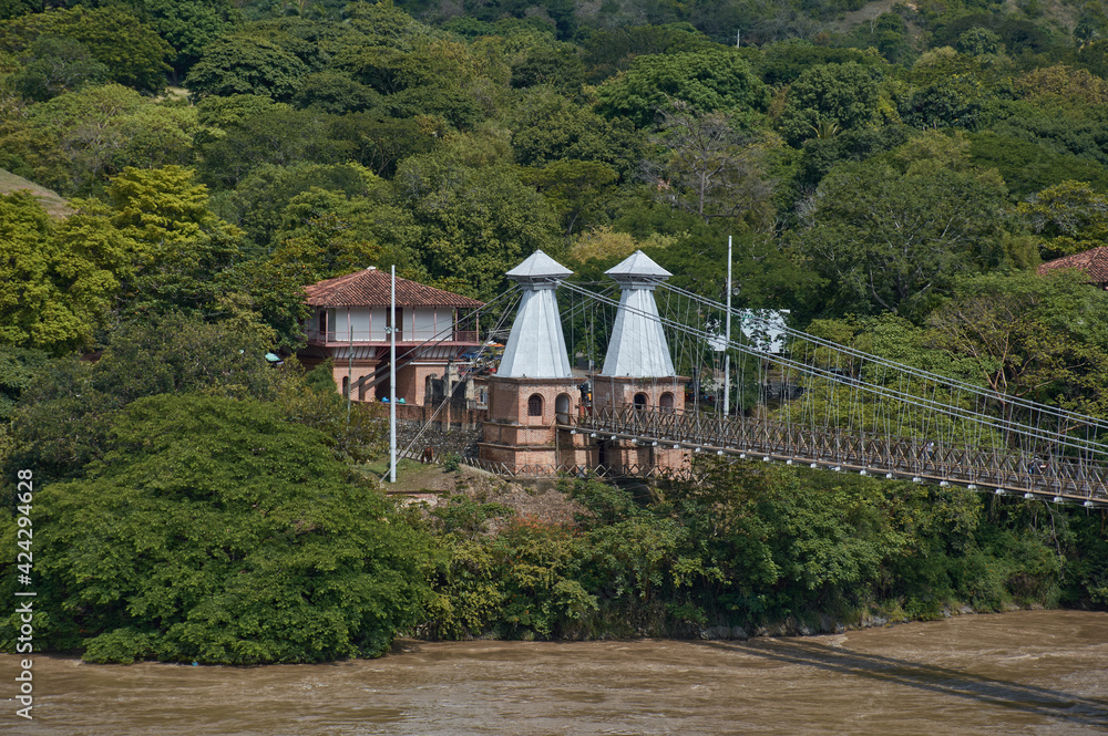 Puente de Occidente in department of Antioquia between a large natural river between the mountain full of green trees in Colombian mountains