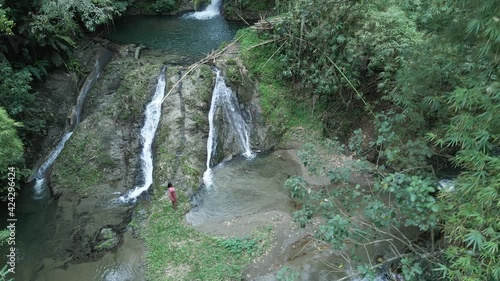 Ascending aerial view of a woman standing at a cascading waterfall in slow motion on the Caribbean island of Tobago photo